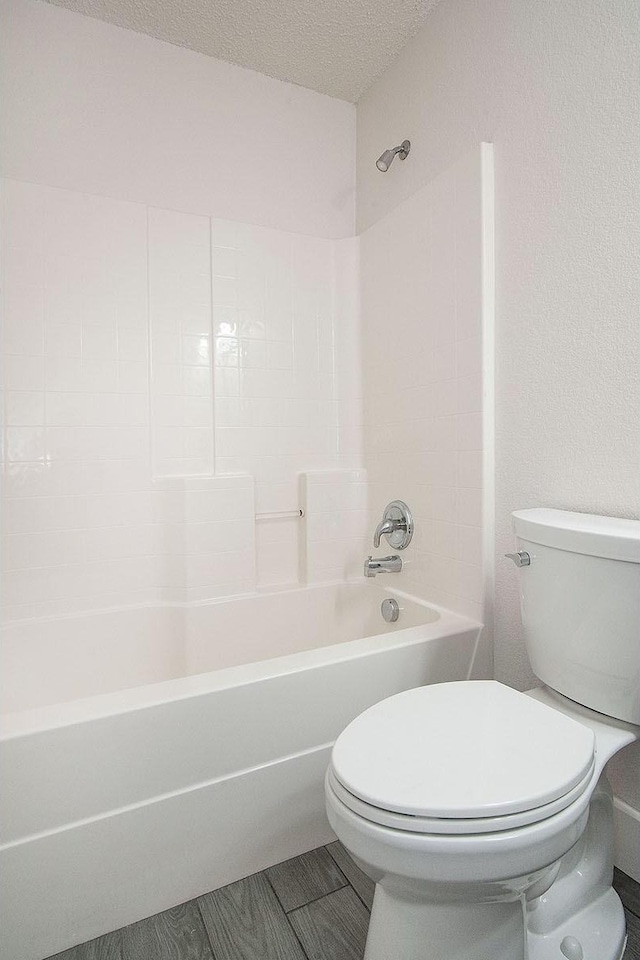 bathroom featuring a textured ceiling, toilet, and shower / bathtub combination