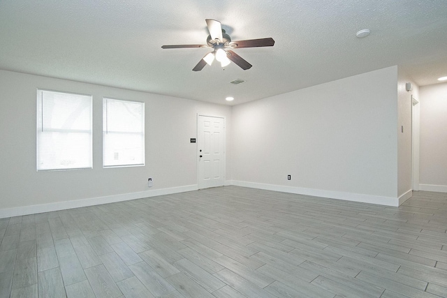 unfurnished room featuring baseboards, visible vents, ceiling fan, wood finished floors, and a textured ceiling