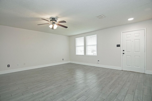 spare room with baseboards, ceiling fan, visible vents, and wood finished floors