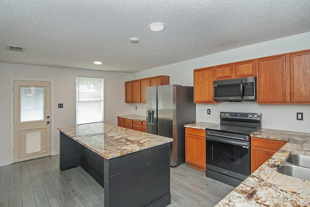 kitchen featuring stainless steel appliances, a center island, and brown cabinets