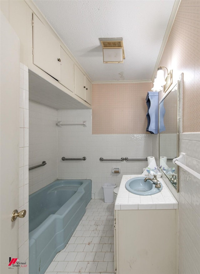 bathroom featuring tile walls, a textured ceiling, vanity, tile patterned flooring, and wallpapered walls