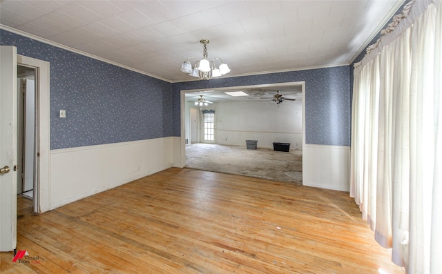 unfurnished dining area featuring ornamental molding, wood-type flooring, wainscoting, and wallpapered walls