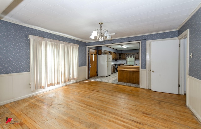 kitchen featuring wallpapered walls, light wood-style flooring, wainscoting, and freestanding refrigerator