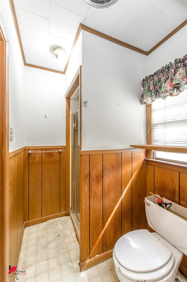 full bath with toilet, a wainscoted wall, wood walls, ornamental molding, and tile patterned floors