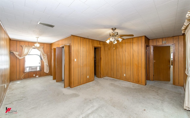 empty room with cooling unit, visible vents, wood walls, and light carpet