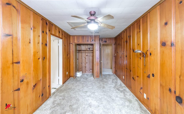 unfurnished room with light carpet, wood walls, and ceiling fan