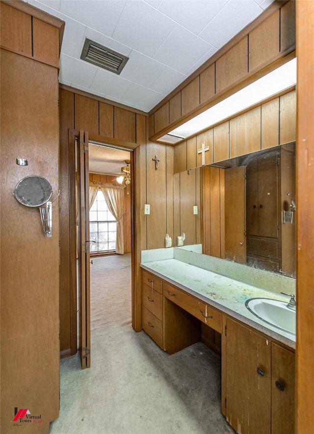 bathroom with visible vents, a sink, and wood walls