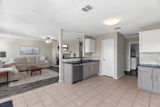 kitchen with a fireplace, visible vents, open floor plan, and stainless steel dishwasher