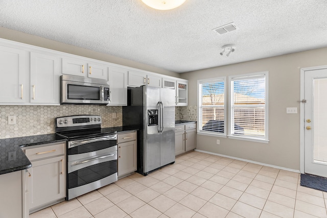 kitchen with light tile patterned flooring, visible vents, white cabinets, appliances with stainless steel finishes, and backsplash