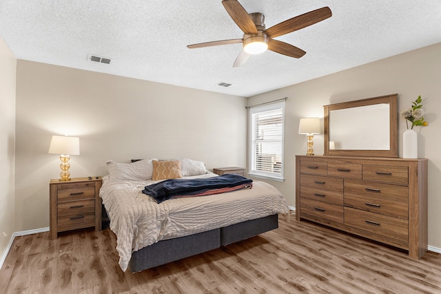 bedroom with light wood-type flooring, visible vents, and a textured ceiling