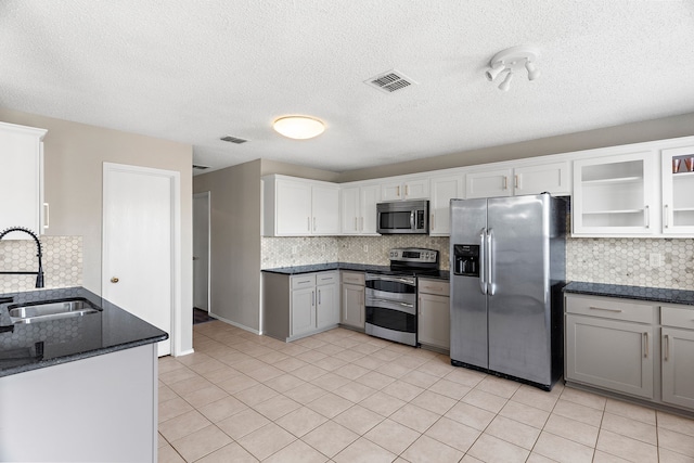 kitchen with appliances with stainless steel finishes, visible vents, a sink, and decorative backsplash