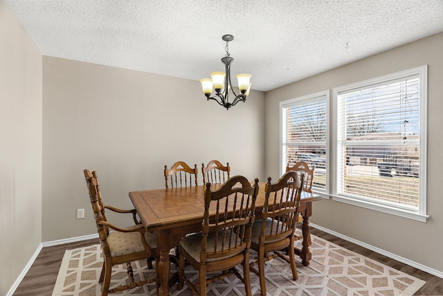 dining room featuring baseboards, a textured ceiling, an inviting chandelier, and light wood-style floors