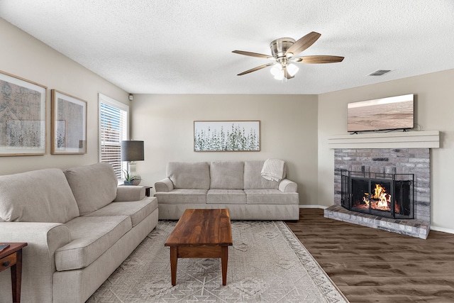 living room with visible vents, ceiling fan, wood finished floors, a textured ceiling, and a fireplace