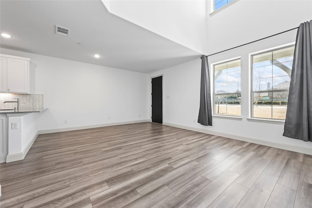 unfurnished living room with light wood finished floors, baseboards, visible vents, and recessed lighting