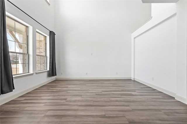 spare room featuring baseboards, a high ceiling, and wood finished floors