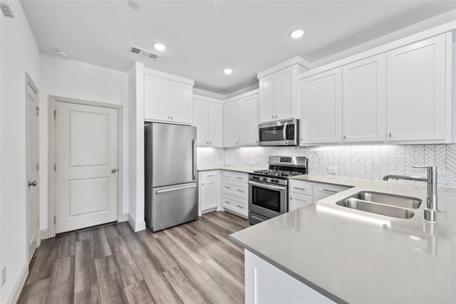 kitchen with light wood-style flooring, a sink, visible vents, appliances with stainless steel finishes, and decorative backsplash