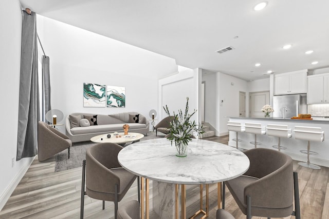 dining space with light wood-type flooring, baseboards, visible vents, and recessed lighting