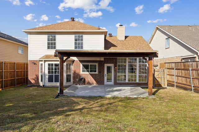 rear view of house featuring a patio area, brick siding, a yard, and a fenced backyard