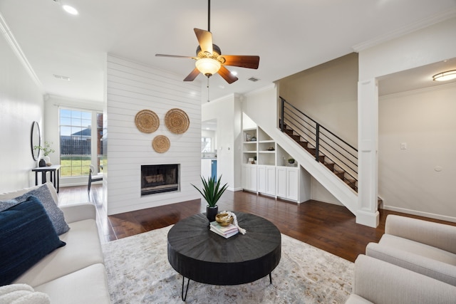 living area with a large fireplace, wood finished floors, and crown molding