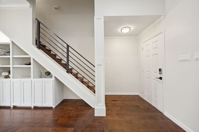 entrance foyer with dark wood-style flooring, crown molding, baseboards, and stairs