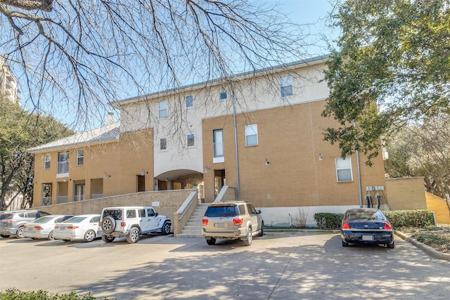 view of property featuring uncovered parking and stairs