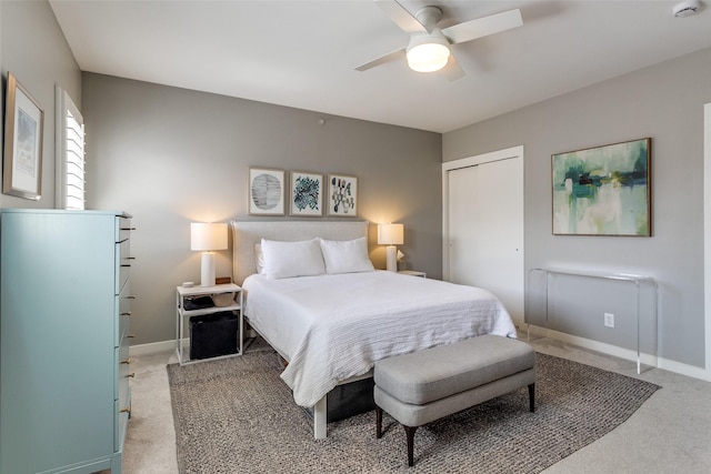 bedroom featuring a closet, baseboards, light colored carpet, and ceiling fan