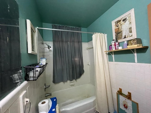 full bathroom with shower / bath combo, wainscoting, and tile walls