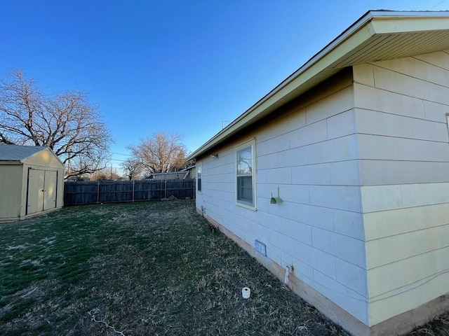 view of home's exterior with a yard, an outdoor structure, fence, and a shed