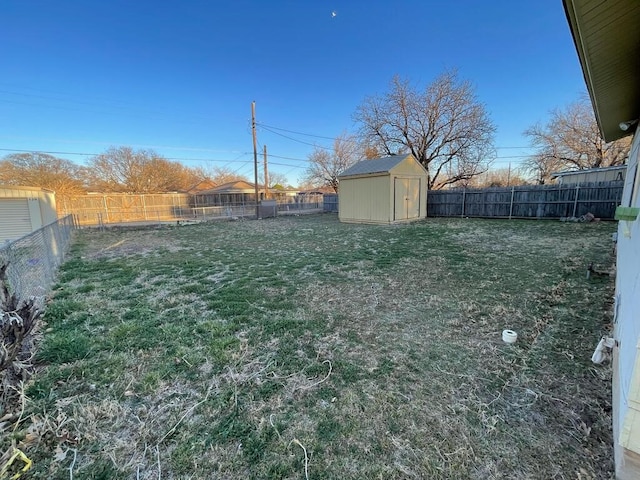 view of yard featuring a shed, a fenced backyard, and an outbuilding