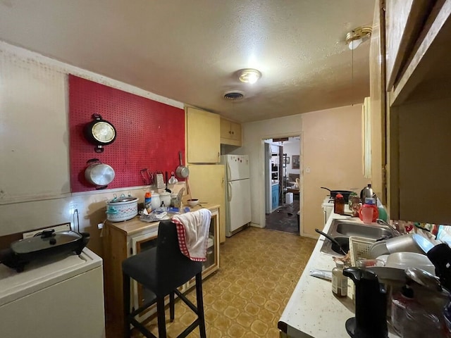 kitchen featuring a sink, visible vents, light countertops, light floors, and washer / clothes dryer