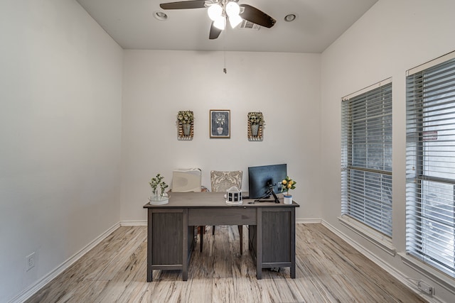 home office with a ceiling fan, visible vents, baseboards, and wood finished floors