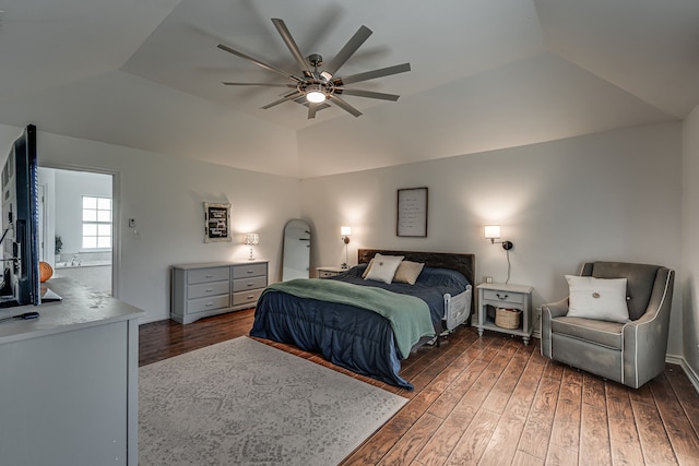 bedroom featuring a tray ceiling, vaulted ceiling, and wood finished floors