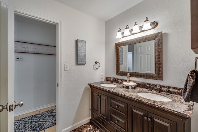 bathroom with a sink, baseboards, and double vanity