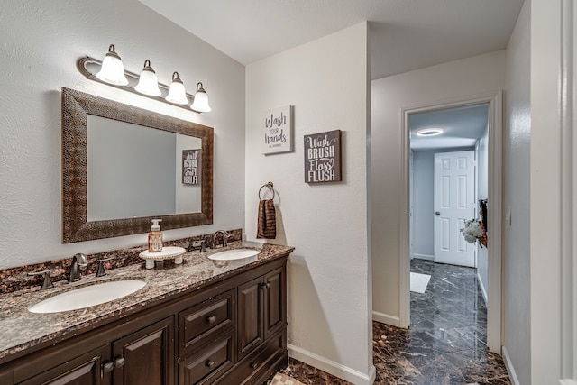 bathroom featuring double vanity, baseboards, and a sink