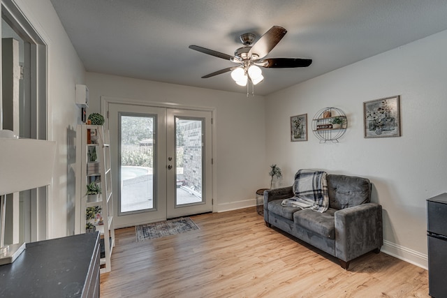 living room with light wood-type flooring, ceiling fan, baseboards, and french doors