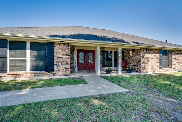 property entrance with a yard, brick siding, and a shingled roof