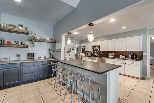 kitchen featuring light tile patterned floors, stainless steel appliances, dark countertops, and a kitchen breakfast bar