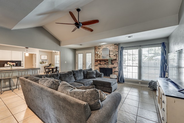 living room featuring a brick fireplace, visible vents, a ceiling fan, and light tile patterned flooring