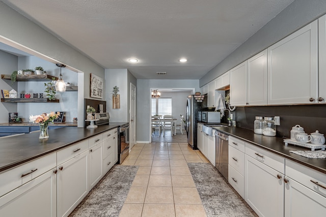 kitchen with dark countertops, light tile patterned floors, white cabinetry, and stainless steel appliances