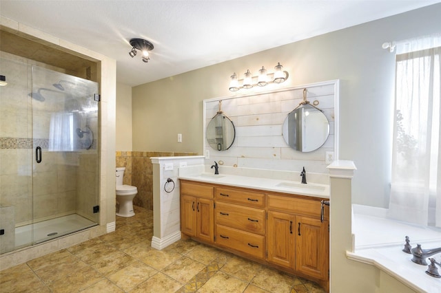 bathroom featuring double vanity, a shower stall, toilet, and a sink