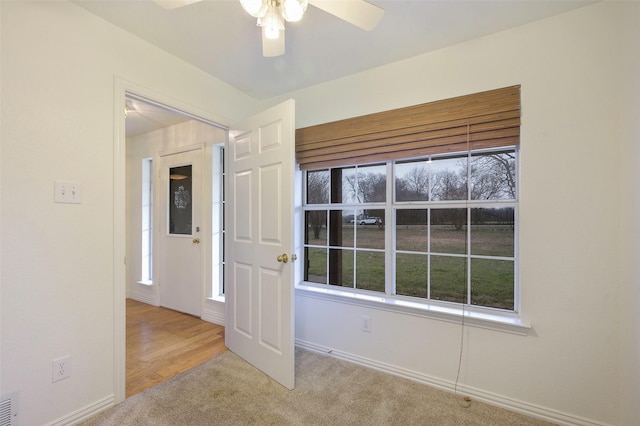 carpeted spare room with ceiling fan and baseboards