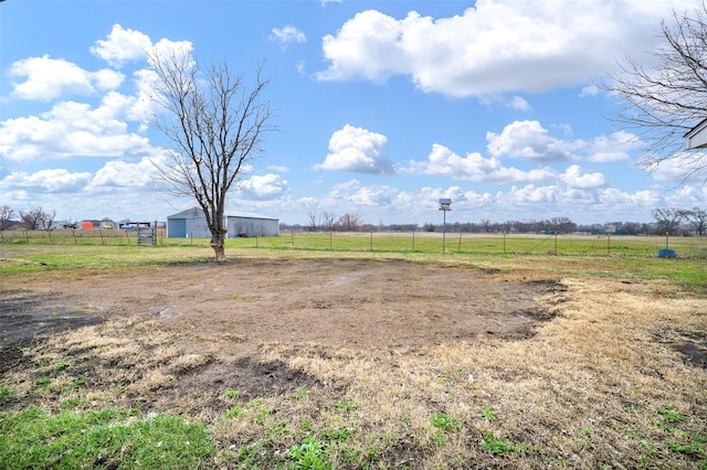 view of yard with fence, an outdoor structure, and a rural view