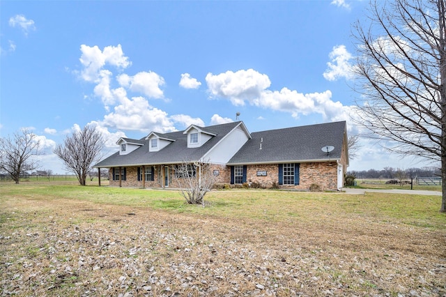 view of front of property featuring a shingled roof, a front lawn, and brick siding