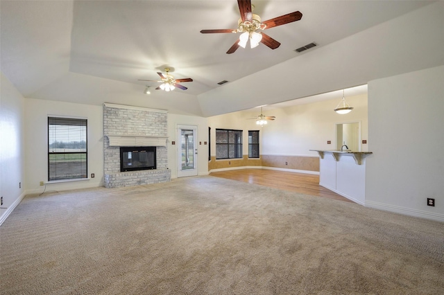 unfurnished living room with light carpet, a fireplace, visible vents, and vaulted ceiling