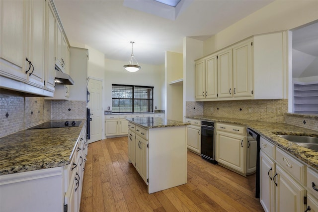 kitchen featuring a kitchen island, light wood-type flooring, under cabinet range hood, dishwashing machine, and black electric cooktop