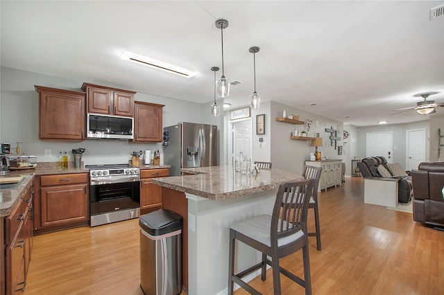 kitchen with stainless steel appliances, a breakfast bar, a kitchen island, visible vents, and light wood-type flooring