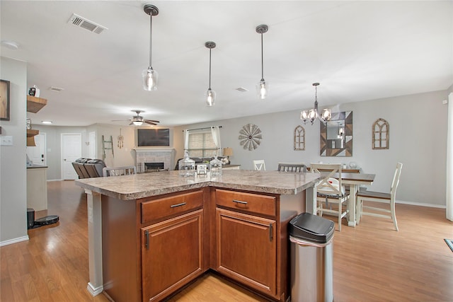 kitchen featuring a fireplace, light countertops, visible vents, light wood-style floors, and a ceiling fan