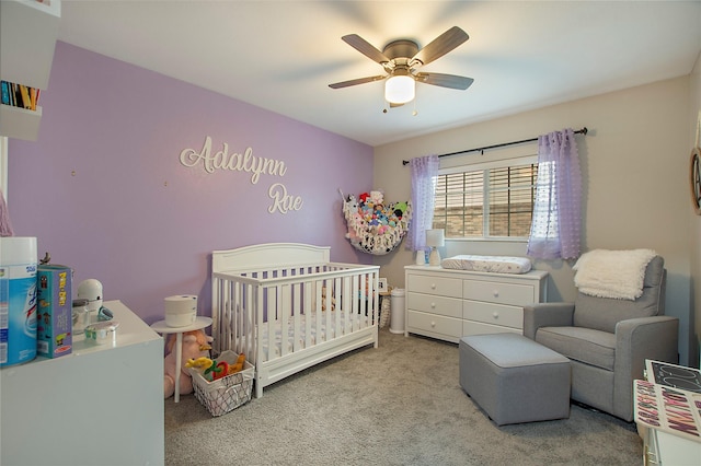 carpeted bedroom with a ceiling fan and a nursery area