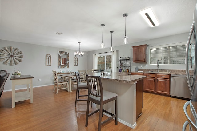 kitchen with visible vents, light wood-style floors, a sink, dishwasher, and a kitchen bar