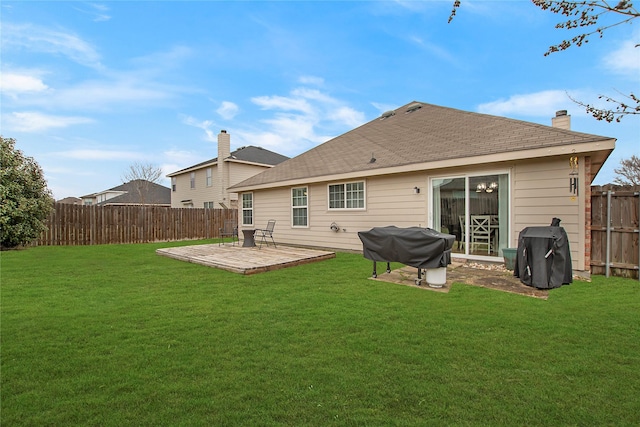 rear view of property featuring a lawn, a fenced backyard, a chimney, roof with shingles, and a wooden deck